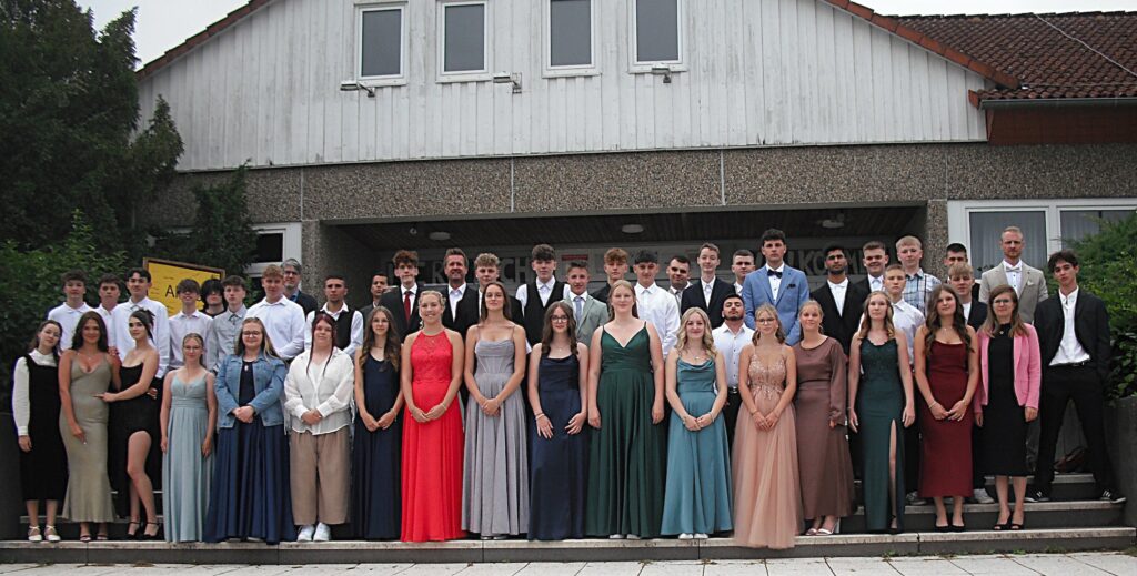 Abschlussschüler und ihre Klassenlehrer auf der Treppe am Schuleingang